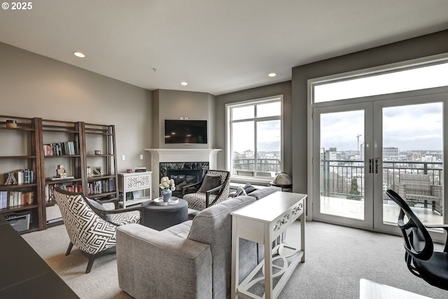 living area featuring recessed lighting, french doors, light colored carpet, and a premium fireplace