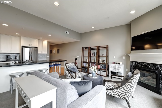 living area with a fireplace, visible vents, carpet flooring, and recessed lighting