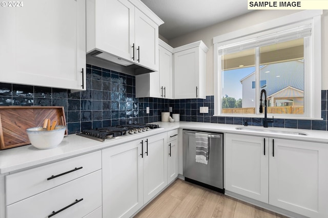 kitchen with sink, white cabinetry, light wood-type flooring, stainless steel appliances, and decorative backsplash