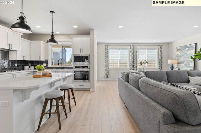 kitchen featuring decorative light fixtures, tasteful backsplash, white cabinetry, a kitchen breakfast bar, and stainless steel appliances