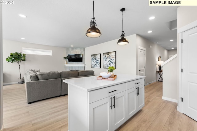 kitchen featuring white cabinetry, light hardwood / wood-style floors, a kitchen island, and pendant lighting