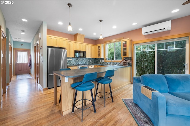 9180 Windward Ln, Manzanita, OR 97130 - kitchen featuring freestanding refrigerator, a wall mounted AC, light brown cabinets, black microwave, and dark countertops