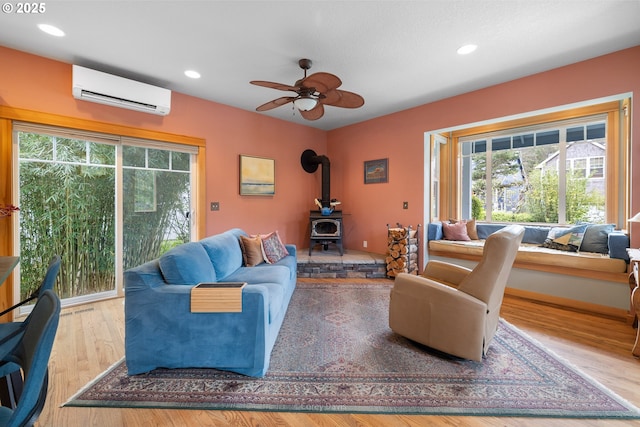 9180 Windward Ln, Manzanita, OR 97130 - living room featuring a wall mounted AC, a wood stove, recessed lighting, a ceiling fan, and wood finished floors