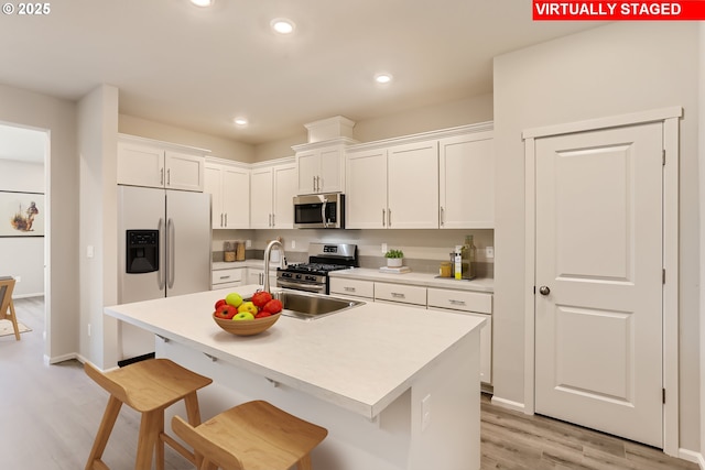 11329 NW Main St, North Plains, OR 97133 - kitchen with a kitchen breakfast bar, stainless steel appliances, light countertops, light wood-style floors, and white cabinetry