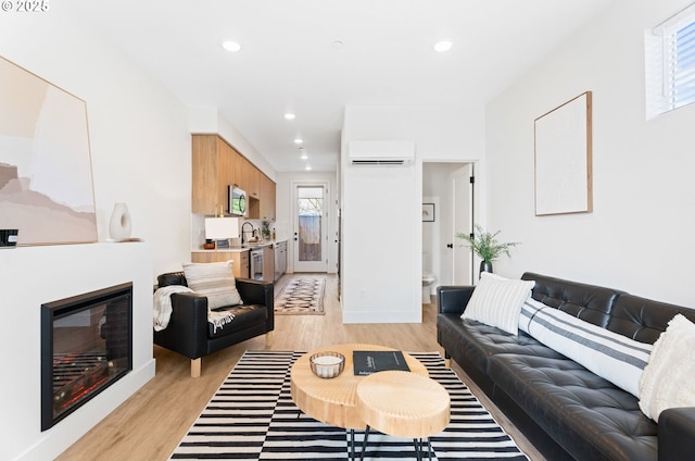 living room featuring a wall mounted air conditioner, sink, and light hardwood / wood-style floors