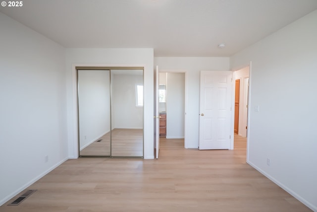 unfurnished bedroom with visible vents, baseboards, a closet, and light wood-style flooring