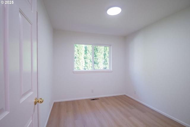 unfurnished room featuring visible vents, light wood-style floors, and baseboards