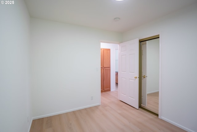 unfurnished bedroom with light wood-style flooring, baseboards, and a closet