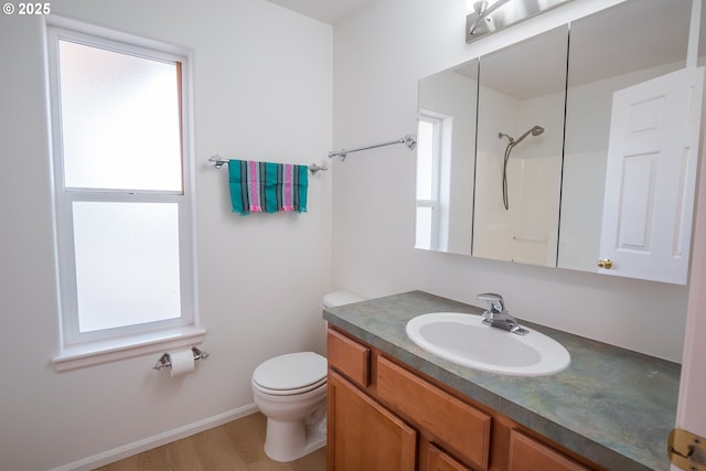 bathroom with toilet, wood finished floors, baseboards, walk in shower, and vanity