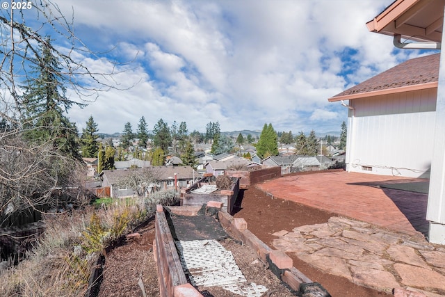 view of yard featuring a patio, fence, and a residential view