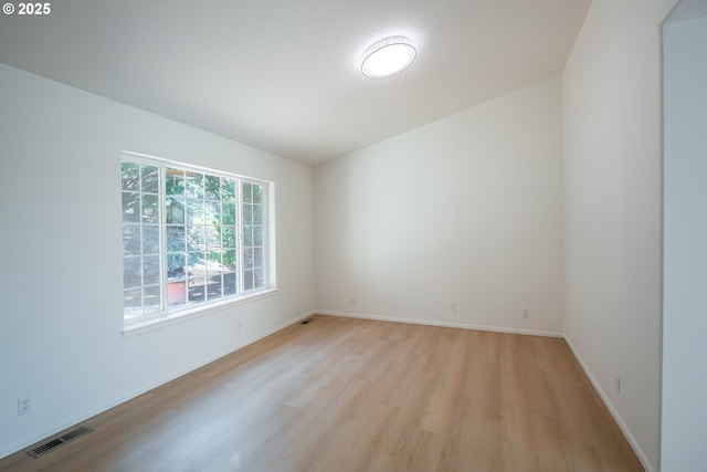 empty room featuring light wood-style flooring, baseboards, and visible vents