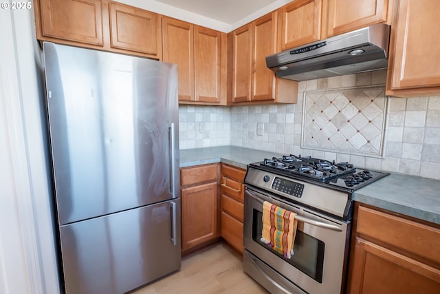 kitchen featuring under cabinet range hood, stainless steel appliances, backsplash, and dark countertops