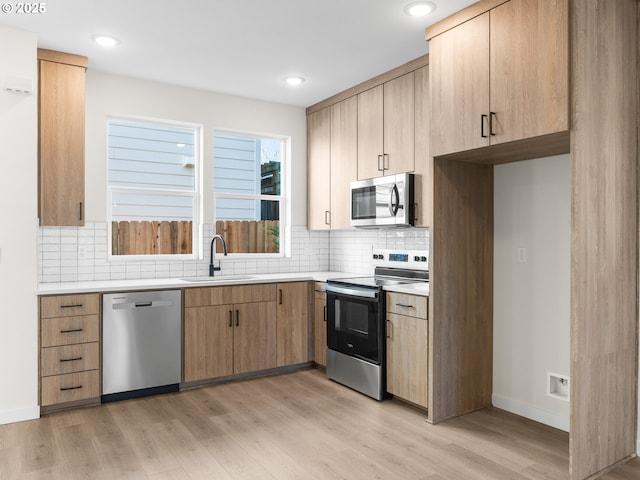 kitchen featuring tasteful backsplash, sink, stainless steel appliances, and light hardwood / wood-style floors