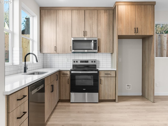 kitchen with sink, light hardwood / wood-style flooring, appliances with stainless steel finishes, a wealth of natural light, and decorative backsplash