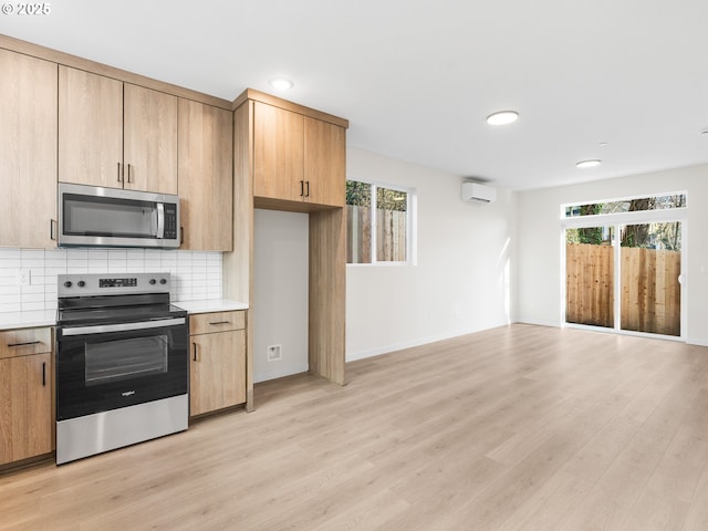 kitchen featuring light hardwood / wood-style flooring, appliances with stainless steel finishes, a wall mounted AC, tasteful backsplash, and light brown cabinets