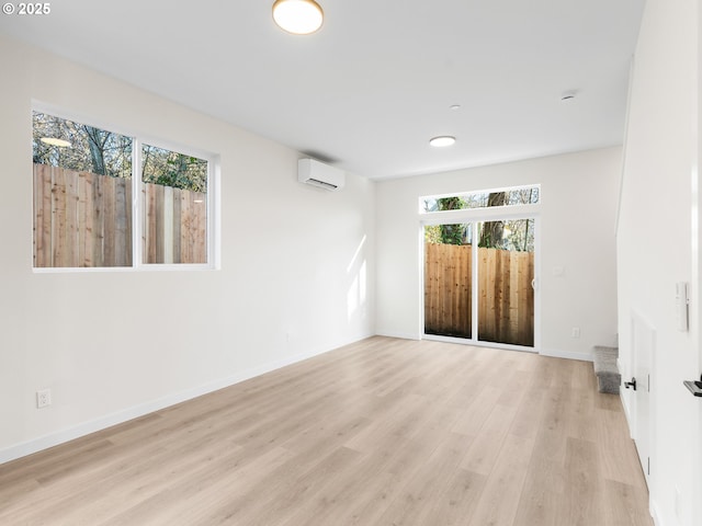 unfurnished room with light hardwood / wood-style floors and an AC wall unit