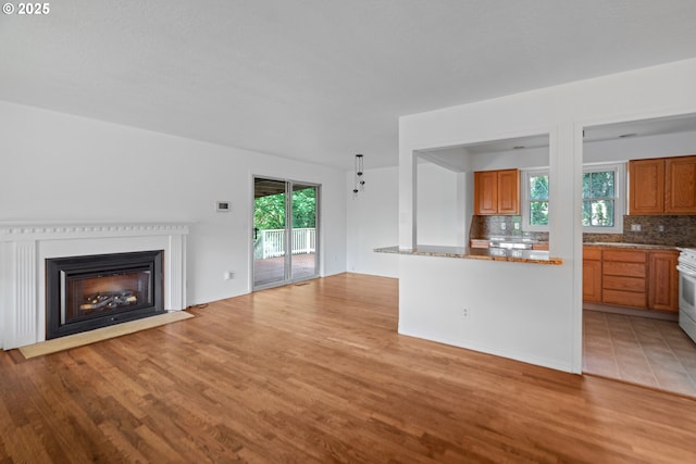 unfurnished living room featuring a fireplace with flush hearth and light wood-style flooring