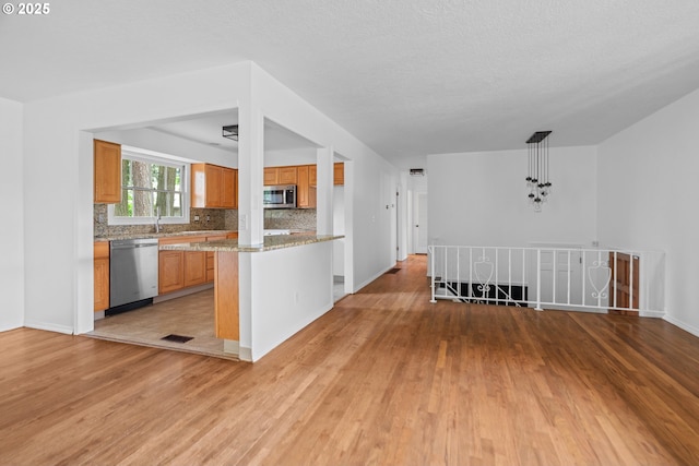 kitchen with tasteful backsplash, stainless steel appliances, light wood-style flooring, and visible vents