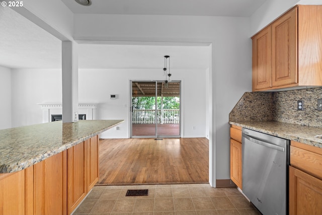 kitchen featuring tasteful backsplash, a fireplace, dishwasher, baseboards, and light stone counters