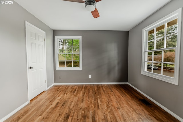 spare room featuring baseboards, ceiling fan, wood finished floors, and visible vents