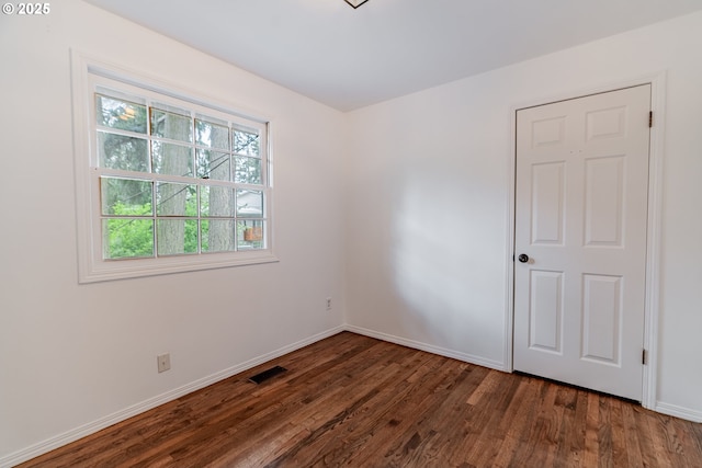 spare room featuring visible vents, baseboards, and wood finished floors