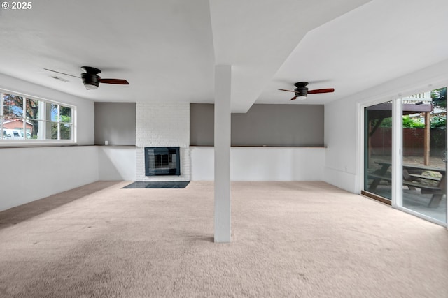 unfurnished living room featuring carpet floors, a ceiling fan, and a brick fireplace