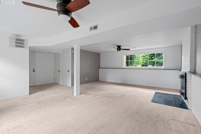unfurnished living room with a ceiling fan, visible vents, carpet, and a fireplace