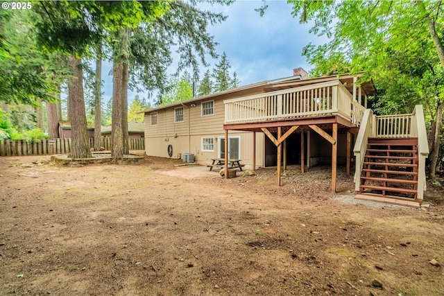 rear view of house featuring stairs, a chimney, a deck, and fence