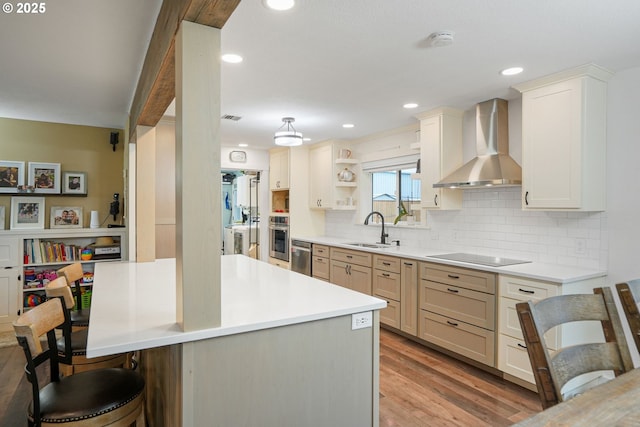 30596 Horseshoe Dr, Albany, OR 97321 - kitchen featuring oven, a breakfast bar, wall chimney range hood, a sink, and black electric stovetop