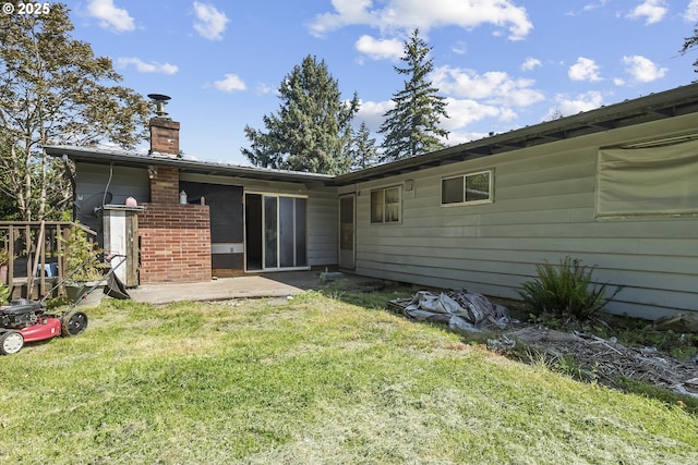 back of house with a chimney, a lawn, and a patio