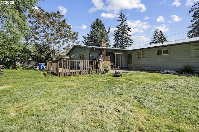 back of house with a chimney, a lawn, and a deck