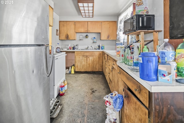 kitchen with freestanding refrigerator, black microwave, concrete floors, and light countertops