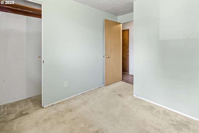 unfurnished bedroom featuring carpet floors, a closet, baseboards, and a textured ceiling