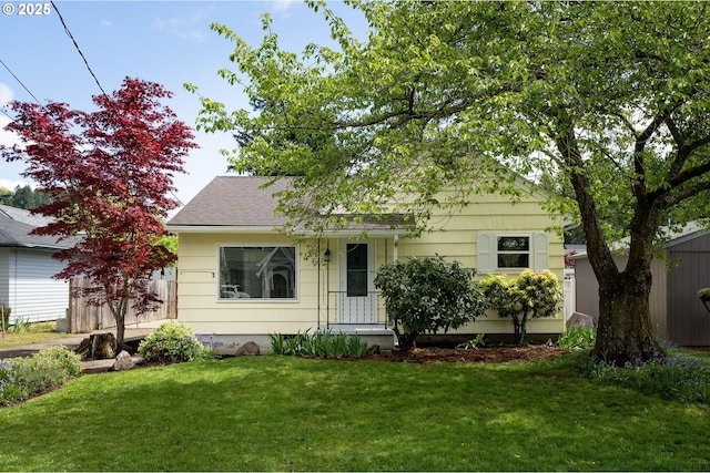 view of front facade featuring roof with shingles and a front lawn