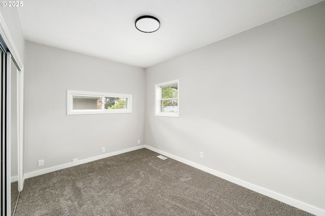 unfurnished bedroom featuring baseboards, a closet, and dark colored carpet