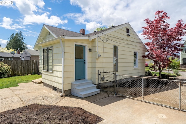 bungalow featuring fence, a chimney, a gate, a shingled roof, and entry steps