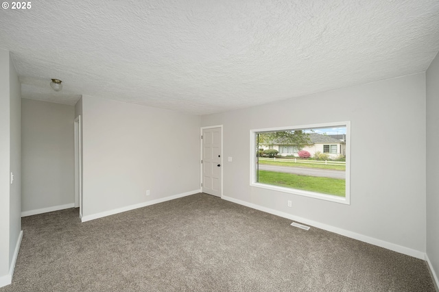 empty room with baseboards, carpet flooring, a textured ceiling, and visible vents