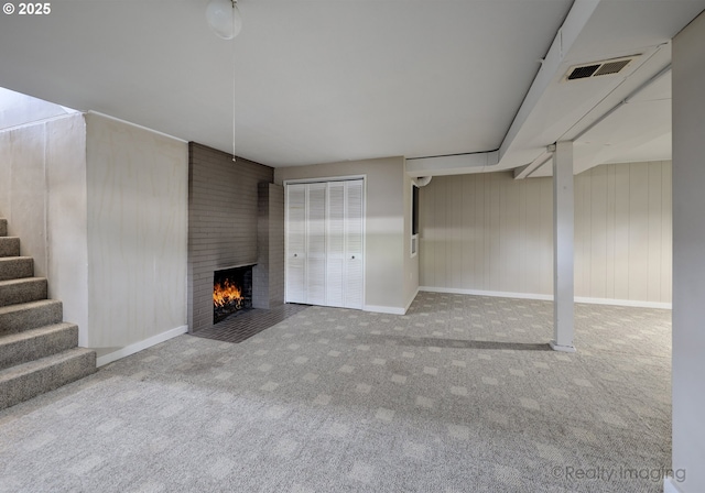 unfurnished living room with stairway, carpet floors, a fireplace, and visible vents