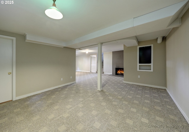finished basement with a brick fireplace, baseboards, and carpet
