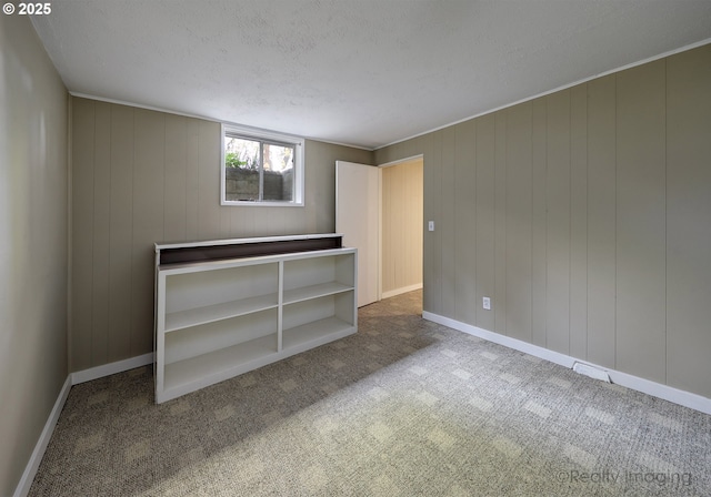 carpeted spare room featuring baseboards and a textured ceiling