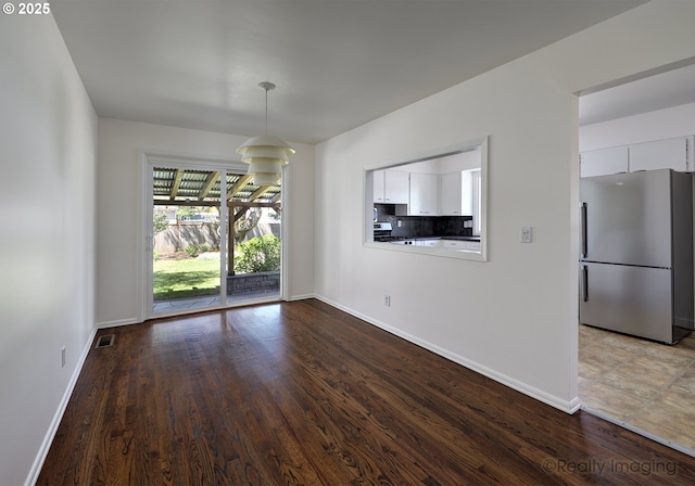 unfurnished dining area featuring baseboards, wood finished floors, and visible vents