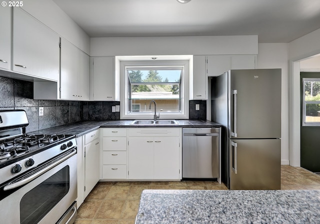 kitchen with white cabinets, appliances with stainless steel finishes, a sink, ventilation hood, and decorative backsplash