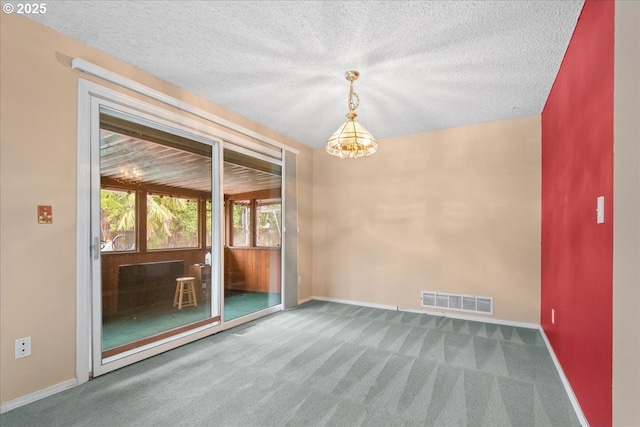 carpeted spare room with a textured ceiling, baseboards, visible vents, and a chandelier