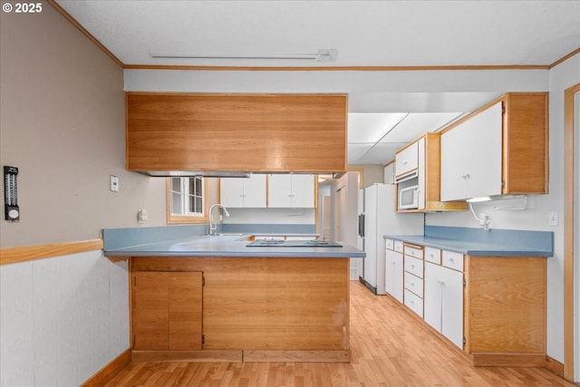 kitchen with crown molding, light wood-style flooring, a peninsula, white appliances, and a sink