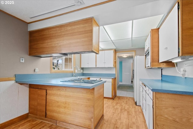 kitchen featuring light wood finished floors, white cabinets, a peninsula, and electric stovetop