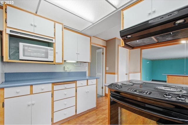 kitchen with under cabinet range hood, white cabinetry, black range with electric cooktop, and light wood-style floors