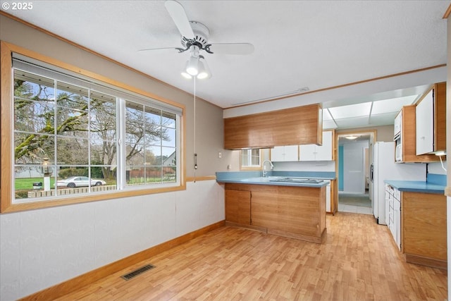 kitchen with a peninsula, visible vents, a wealth of natural light, and light wood-type flooring