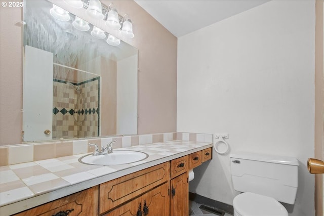 bathroom with visible vents, toilet, baseboards, tiled shower, and vanity