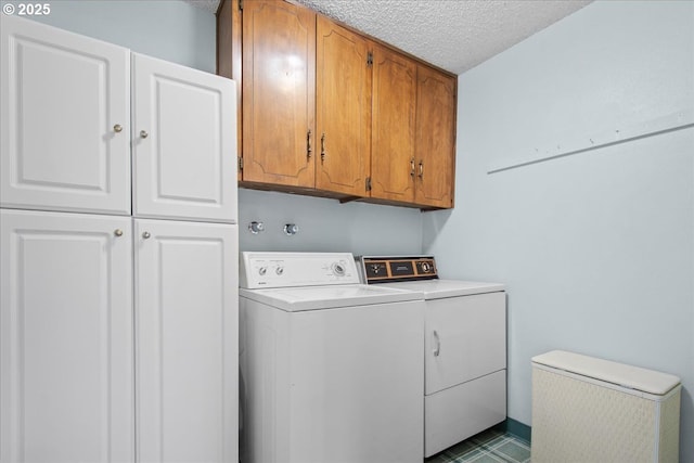 clothes washing area featuring cabinet space, separate washer and dryer, and a textured ceiling