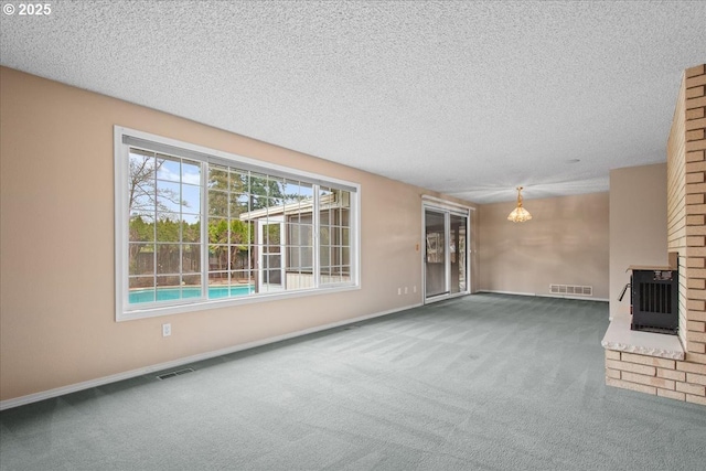 unfurnished living room featuring visible vents, a brick fireplace, a chandelier, and carpet flooring